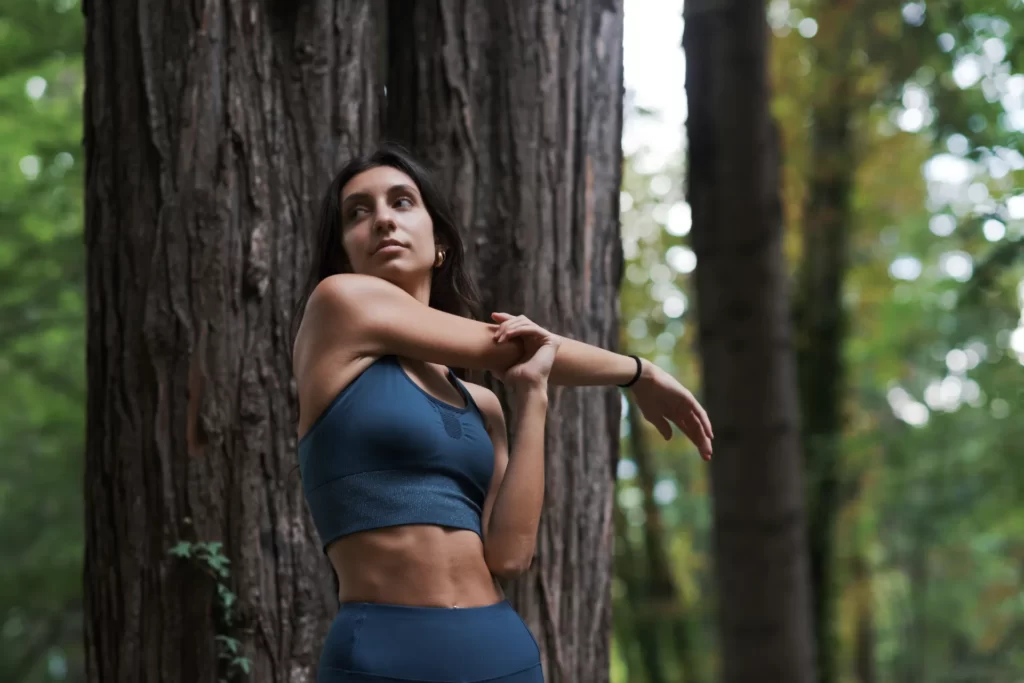 woman doing stretching exercises in the forest utc